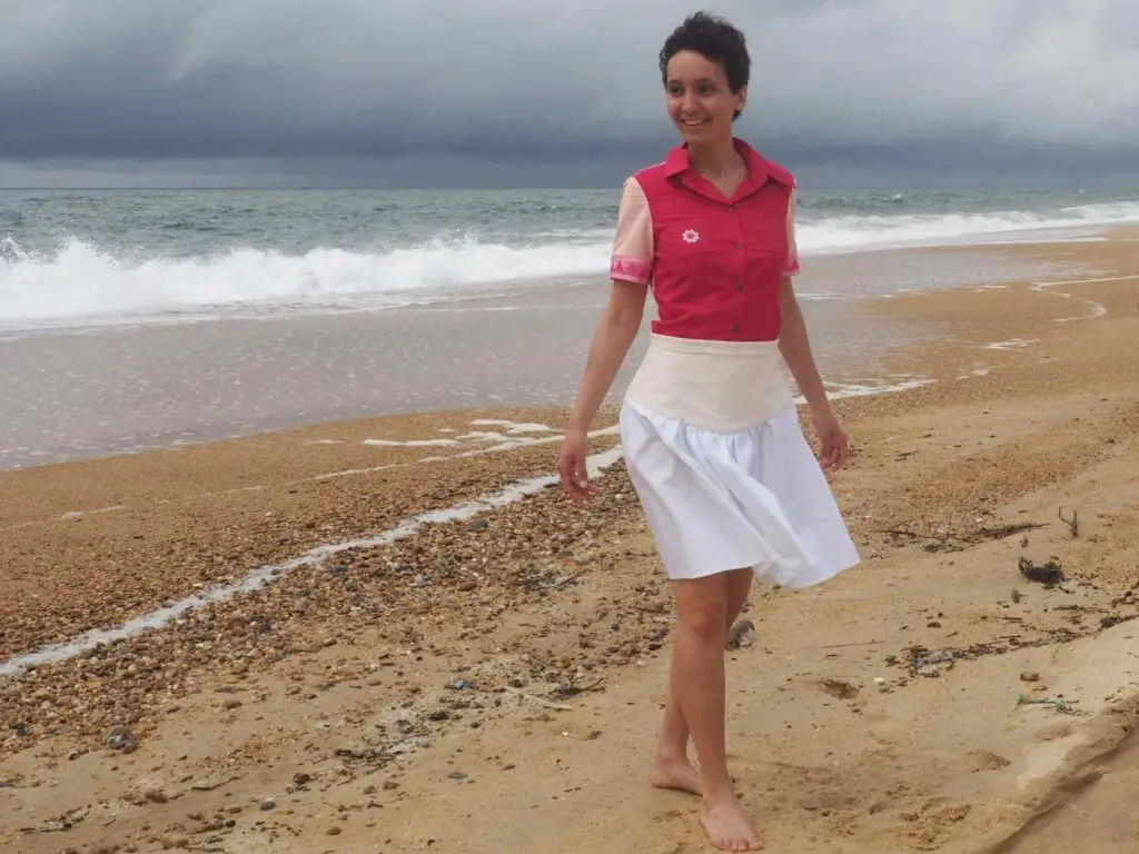 Femme portant une jupe blanche courte et brodée avec des poches, faite à Bayonne.